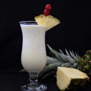 A refreshing pina colada garnished with fresh pineapple slices, ideal for tropical settings.