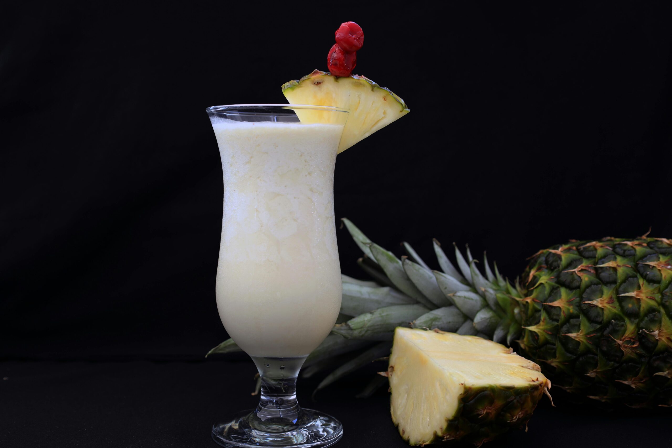 A refreshing pina colada garnished with fresh pineapple slices, ideal for tropical settings.